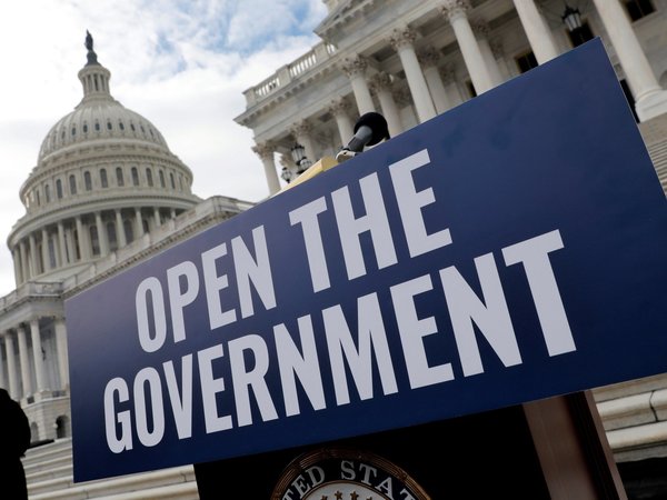 Blue sign that reads "OPEN THE GOVERNMENT" in white text on a podium in front of the capitol building